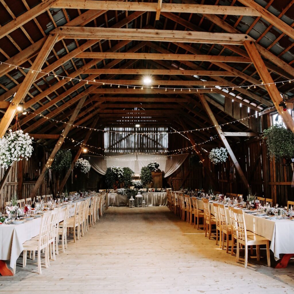 Interieur einer alten Holzhalle mit dekorierten Tischen.